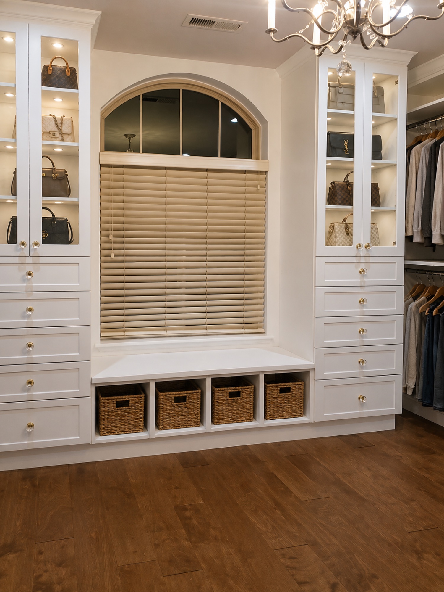 Primary master closet with cream melamine, gold-accented glass knobs, windowed cabinetry, and a seating area