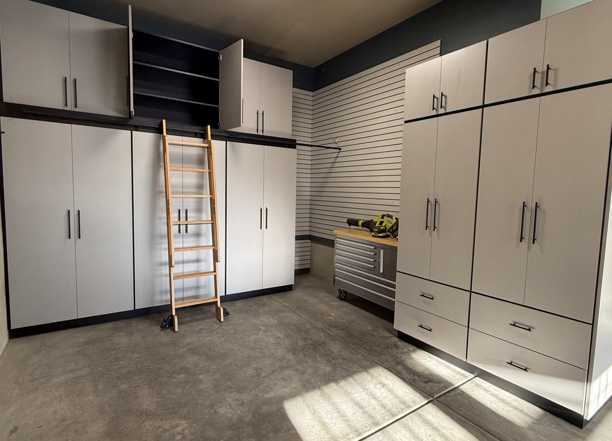 Custom garage storage with workbench, slatwall, and ladder